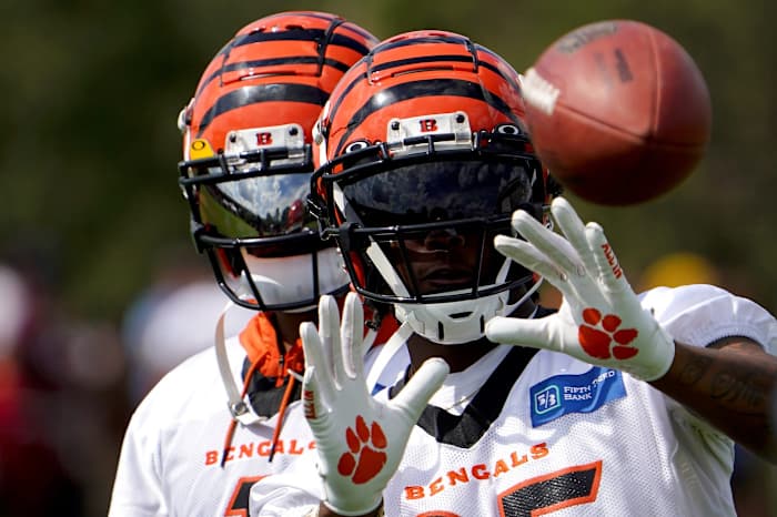 Cincinnati Bengals wide receiver Tee Higgins (85) catches passes from Jugs football passing machine as wide receiver Ja'Marr Chase (1), background, assists at the conclusion of Cincinnati Bengals training camp practice, Friday, July 29, 2022, at the practice fields next to Paul Brown Stadium in Cincinnati. Cincinnati Bengals Training Camp July 29 0033
